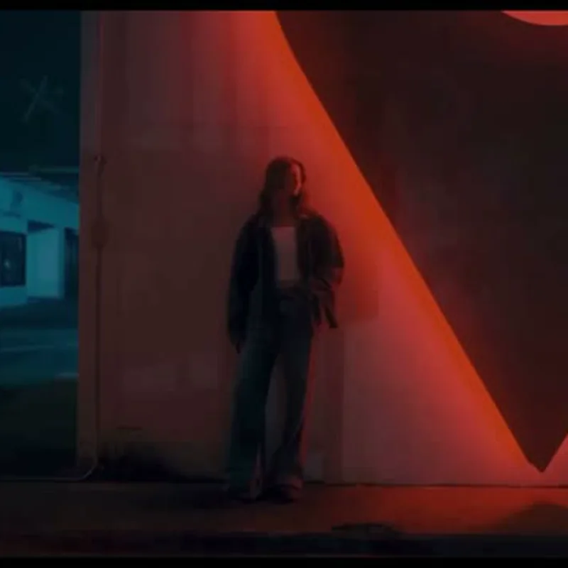 Mujer de pie en un espacio arquitectónico iluminado en rojo y azul
